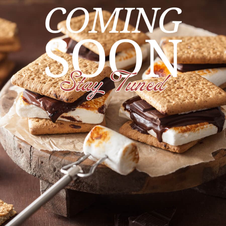 A plate of s'mores with a roasting stick, overlaid with "COMING SOON" text.