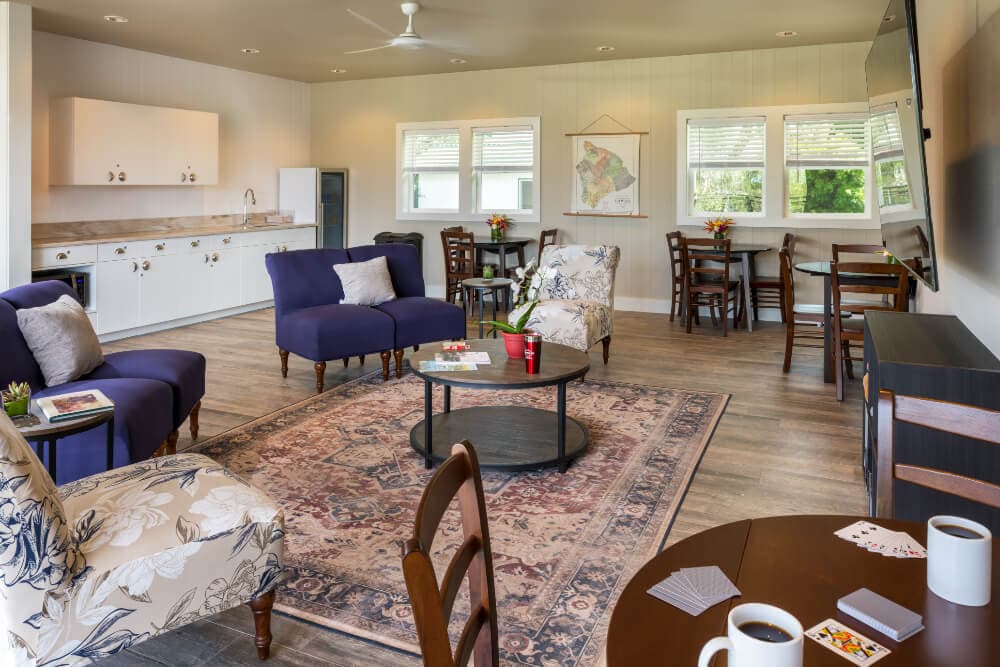 A cozy living space featuring colorful seating, a coffee table, a dining area, and a kitchen.